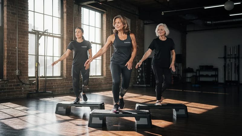 Gruppe trainiert Aerobic auf Steppbrettern in einem hellen Studio
