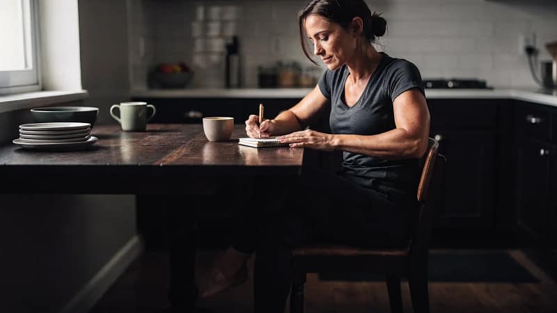 Frau notiert nach dem Training ihre Werte in ein Trainingstagebuch